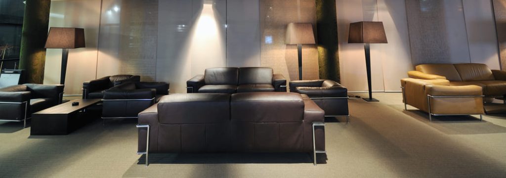 Sala de exposición moderna con sofás de cuero y lámparas de pie.