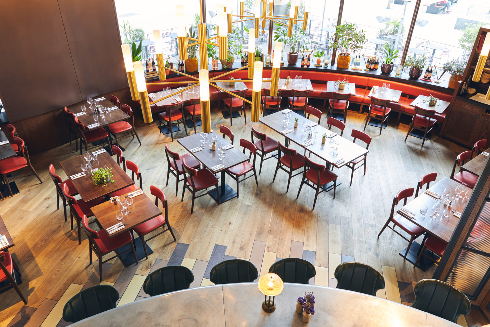 Vista aérea de un restaurante moderno con mesas de madera y sillas rojas.