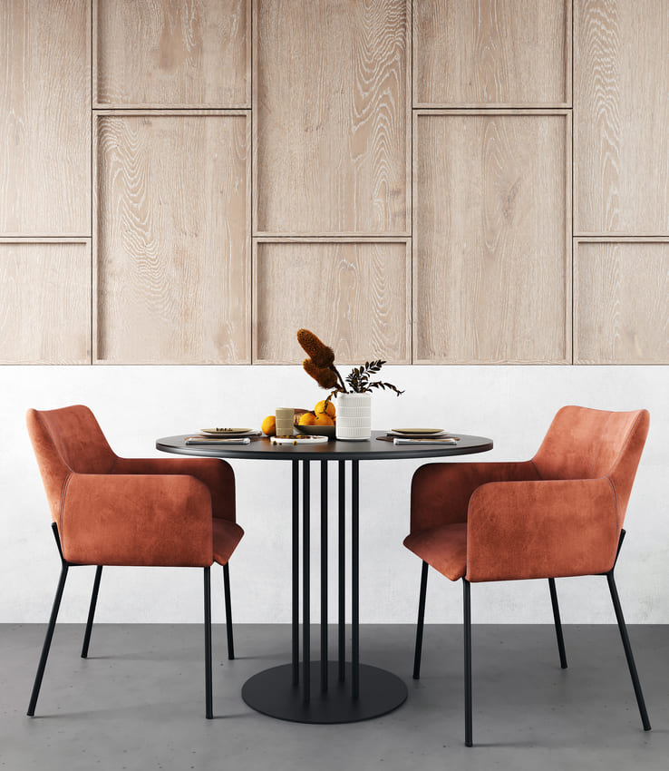 Mesa de comedor moderna con sillas de terciopelo naranja y una pared de paneles de madera al fondo.