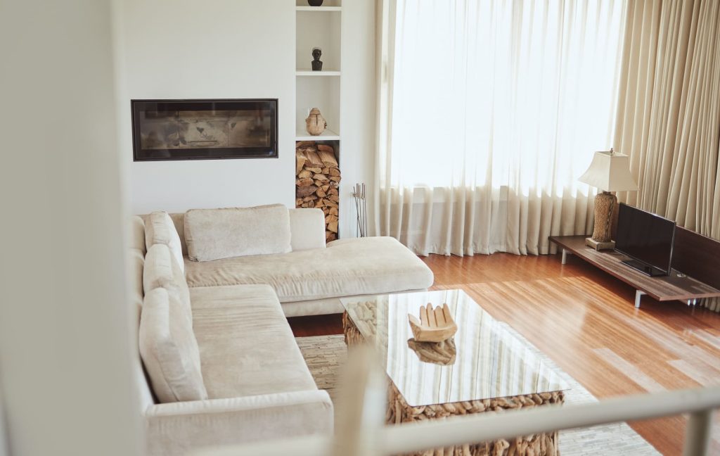 Sala de estar acogedora con sofá de terciopelo, chimenea y luz natural.