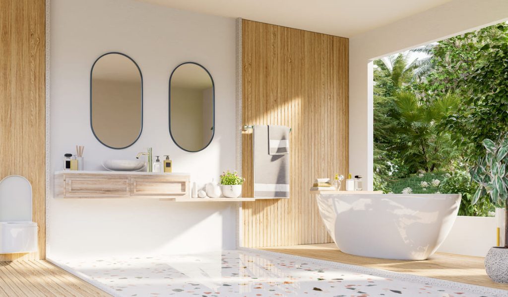 Baño moderno y luminoso con detalles de madera y vista a un jardín tropical.
